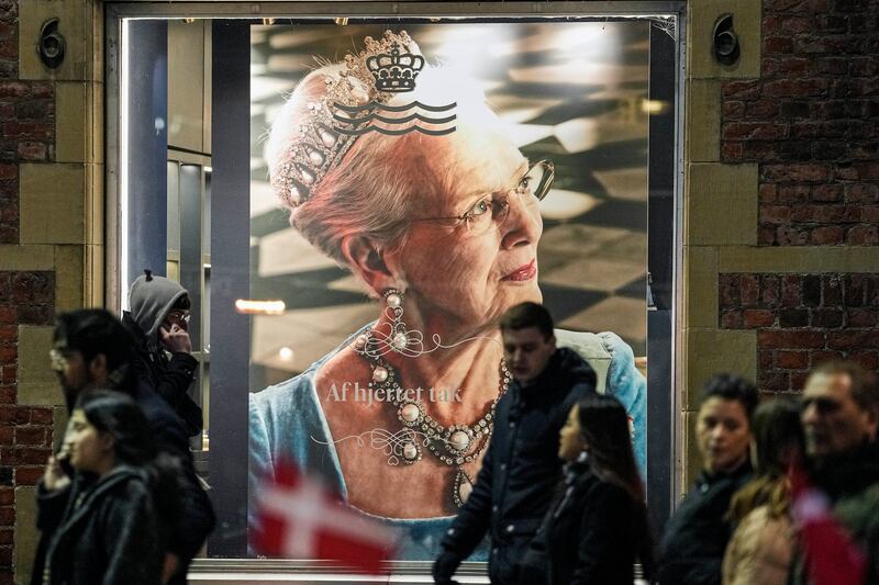 People pass a picture of Danish Queen Margrethe II displayed in a window in a shopping street in Copenhagen (Martin Meissner/AP)