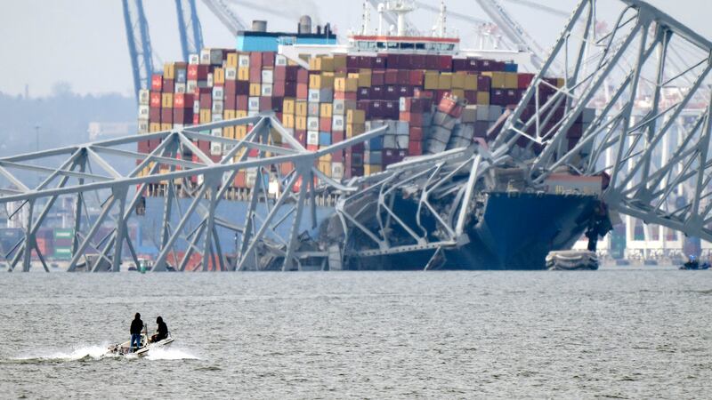 A boat moves near the container ship Dali as it rests against wreckage of the Francis Scott Key Bridge (Mark Schiefelbein/AP)