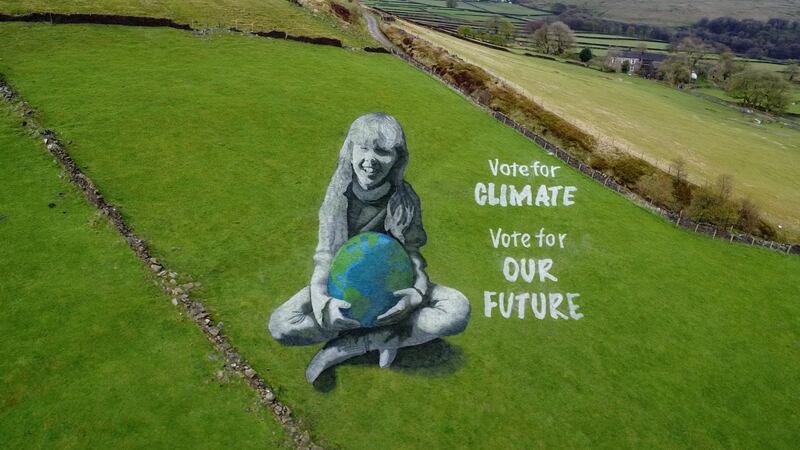A huge anamorphic painting of a girl holding the Earth has been created in the West Yorkshire countryside to mark Earth Day