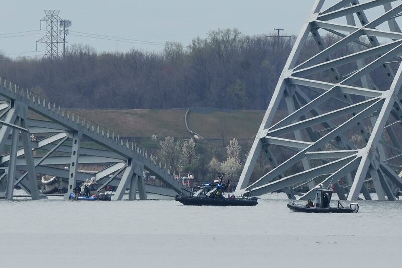 Boats move near a container ship as it rests against wreckage of the Francis Scott Key Bridge (Matt Rourke/AP)