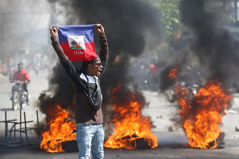 A demonstrator holds up a Haitian flag during protests earlier in the month (AP Photo/Odelyn Joseph)