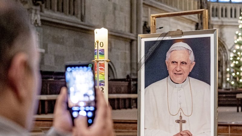 A person takes a picture of a portrait of Pope Emeritus Benedict XVI at St. Peter&#39;s Cathedral in Regensburg, Germany 
