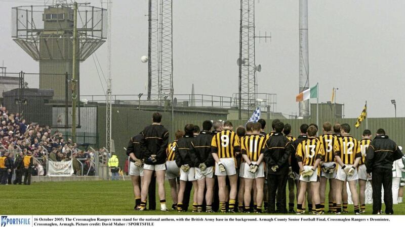 The Crossmaglen Rangers team stand for the national anthem, with the British Army base in the background. 