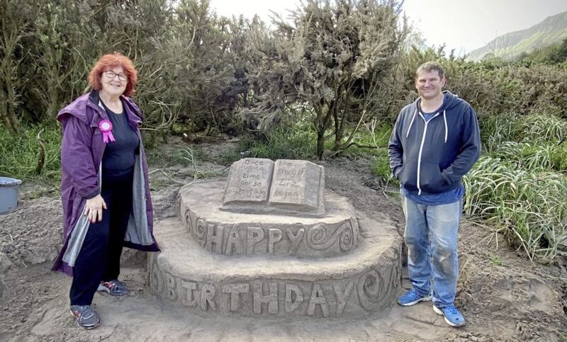 Sand artist Andrew Difford creates a large surprise birthday cake from sand on Waterfoot Beach, Co Antrim for local storyteller Liz Weir. Picture by Mal McCann 