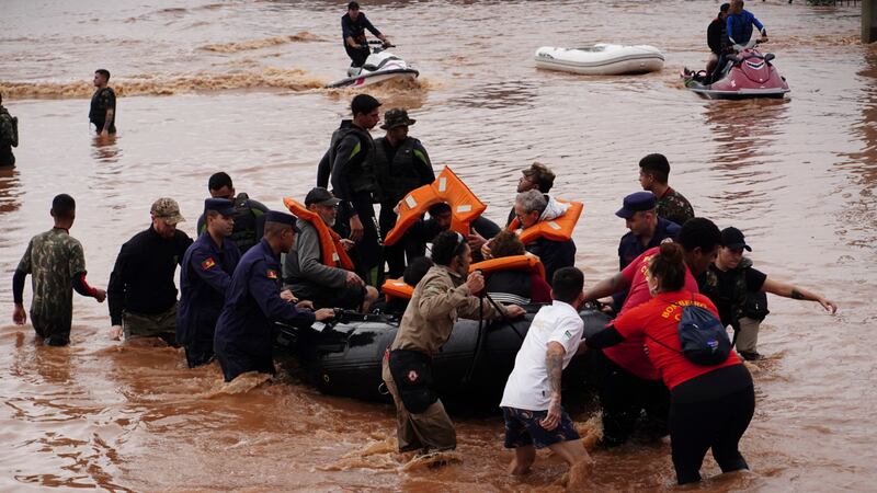 Firefighters and volunteers pull in a boat transporting people rescued from flooding in Brazil ion (Carlos Macedo/AP)