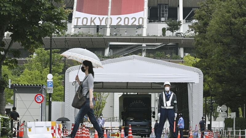 People wearing face masks walk past the National Stadium in Tokyo, Thursday, July 8, 2021 (Kyodo News via AP)&nbsp;