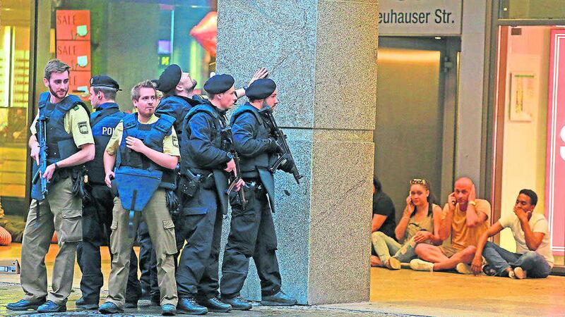 People take shelter on Friday as armed police officers hunt for fugitives after a shooting in a shopping mall in Munich. Picture by Wael Ladki, Associated Press