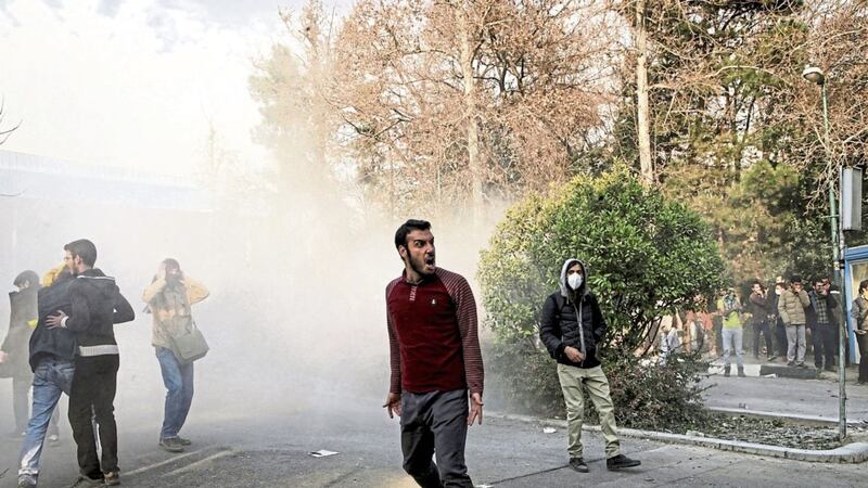 Students attend a protest inside Tehran University last week while a smoke grenade is thrown by anti-riot Iranian police 