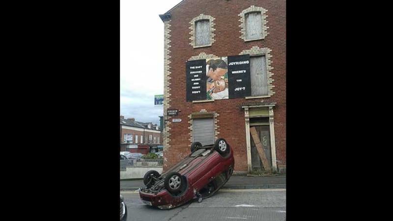 An overturned car at Duncairn Avenue in north Belfast, underneath an anti-car crime mural. Picture by Nuala McAllister Hart