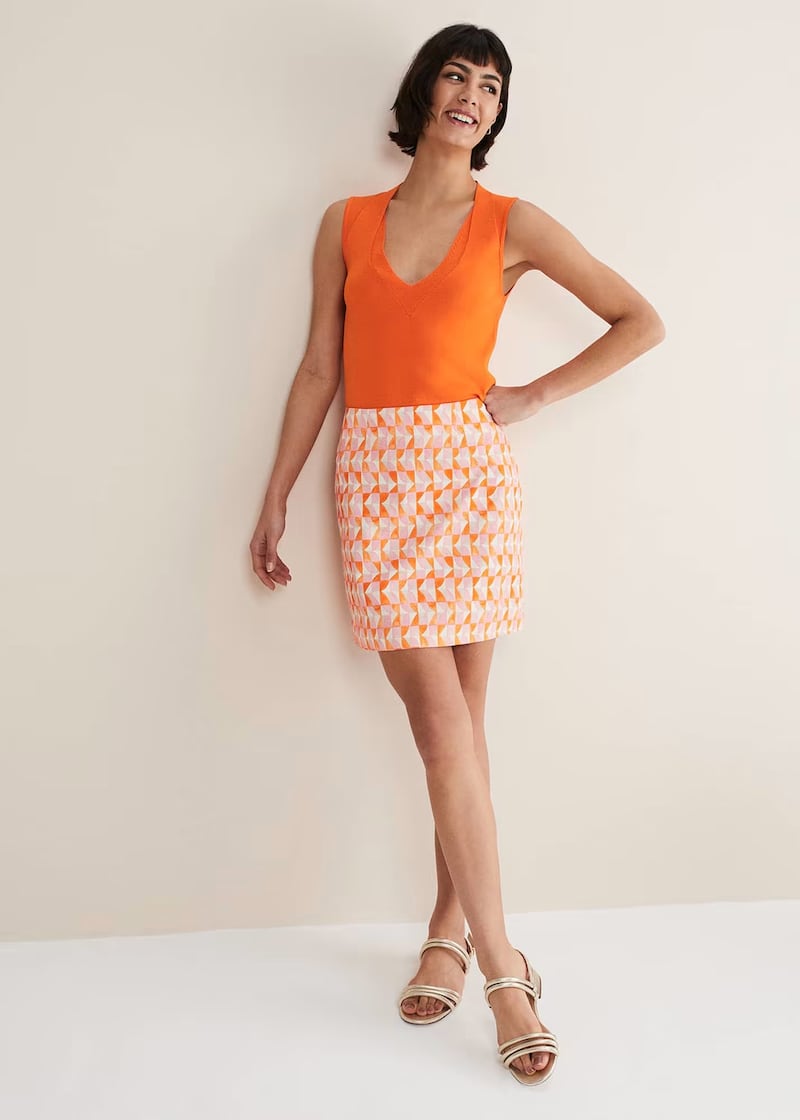 Model dressed in orange vest top and mini skirt