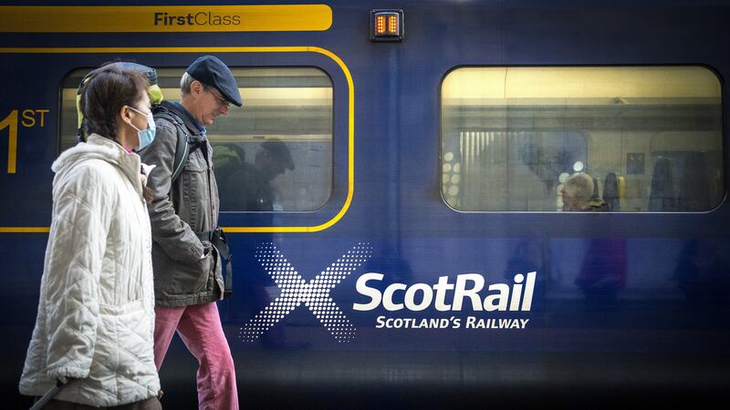 Stock image of commuters passing a ScotRail train