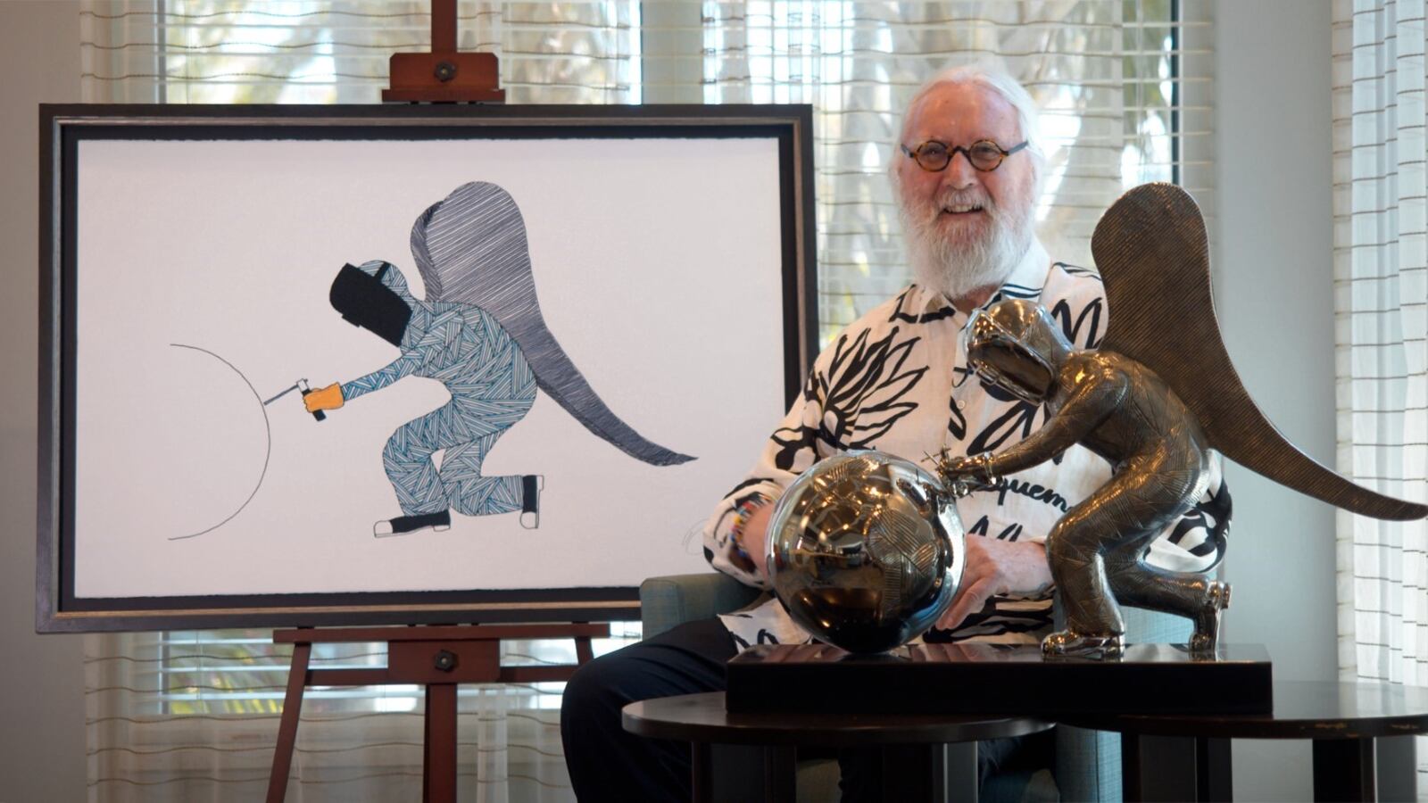 Billy Connolly sits next to his newest painting and sculpture, And On Monday, God Made the World