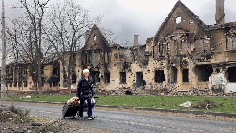 A woman pulls her bags past houses damaged during fighting in Mariupol, eastern Ukraine (AP Photo/Alexei Alexandrov). 