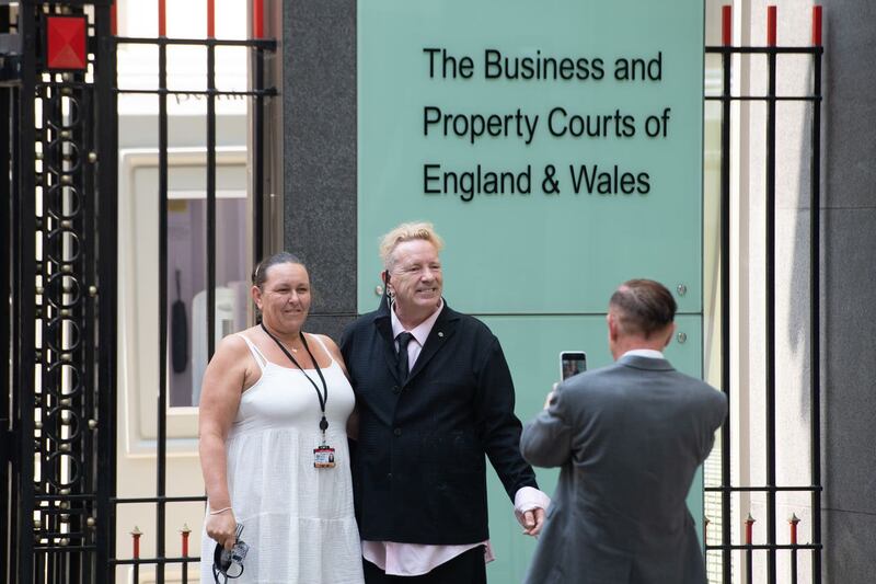 John Lydon, centre, poses for a photo outside the Rolls Building at the High Court 