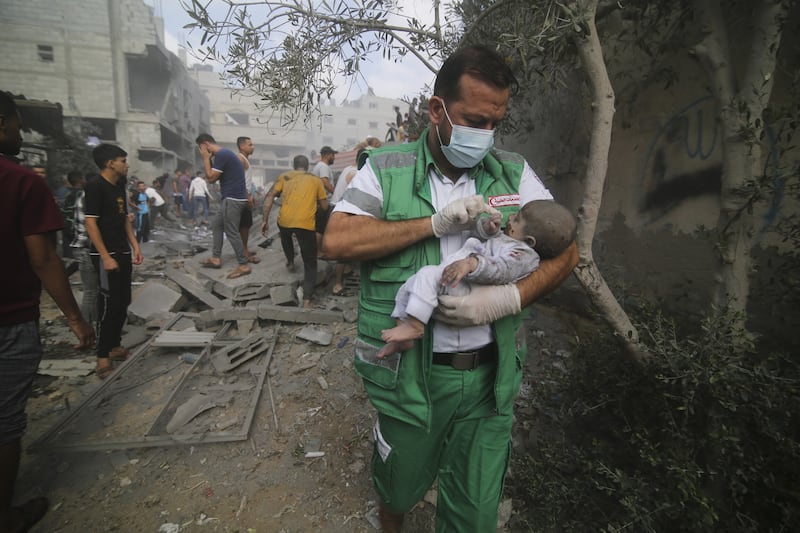 A Palestinian medic carries a baby pulled out of destroyed buildings in the Gaza Strip. Picture by Hatem Ali, AP
