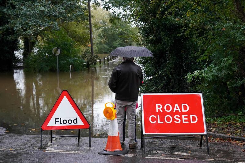 Local residents observe the flooded Carlton Ferry Lane in the village of Collingham in Nottinghamshire after Storm Babet passed through the area