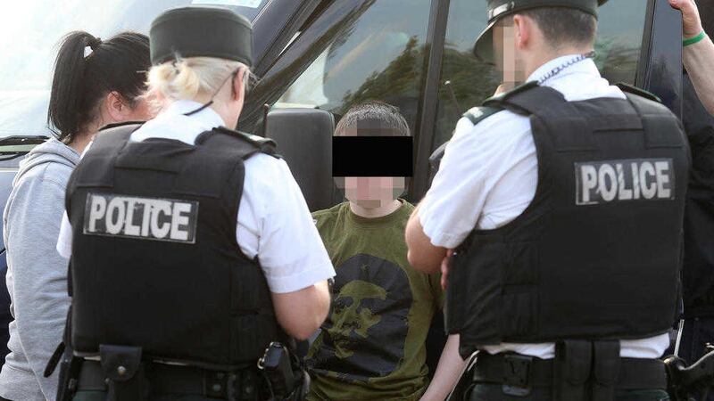 Police question a young boy after twelve men were arrested following an un-notified dissident republican parade in Lurgan, County Armagh on Saturday Picture Mal McCann. 
