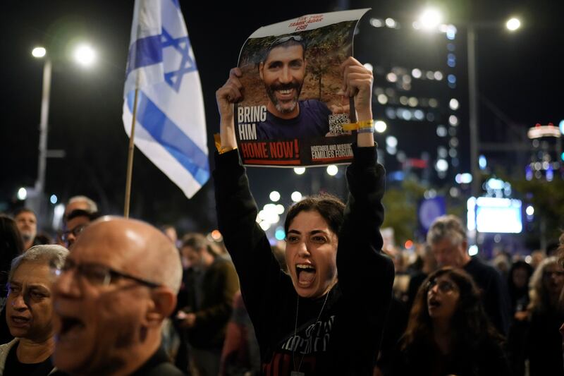 Families and supporters of Israeli hostages held by Hamas in Gaza hold their photographs and shout slogans at a rally calling for their return, in Tel Aviv, Israel, on Saturday (Leo Correa/AP)
