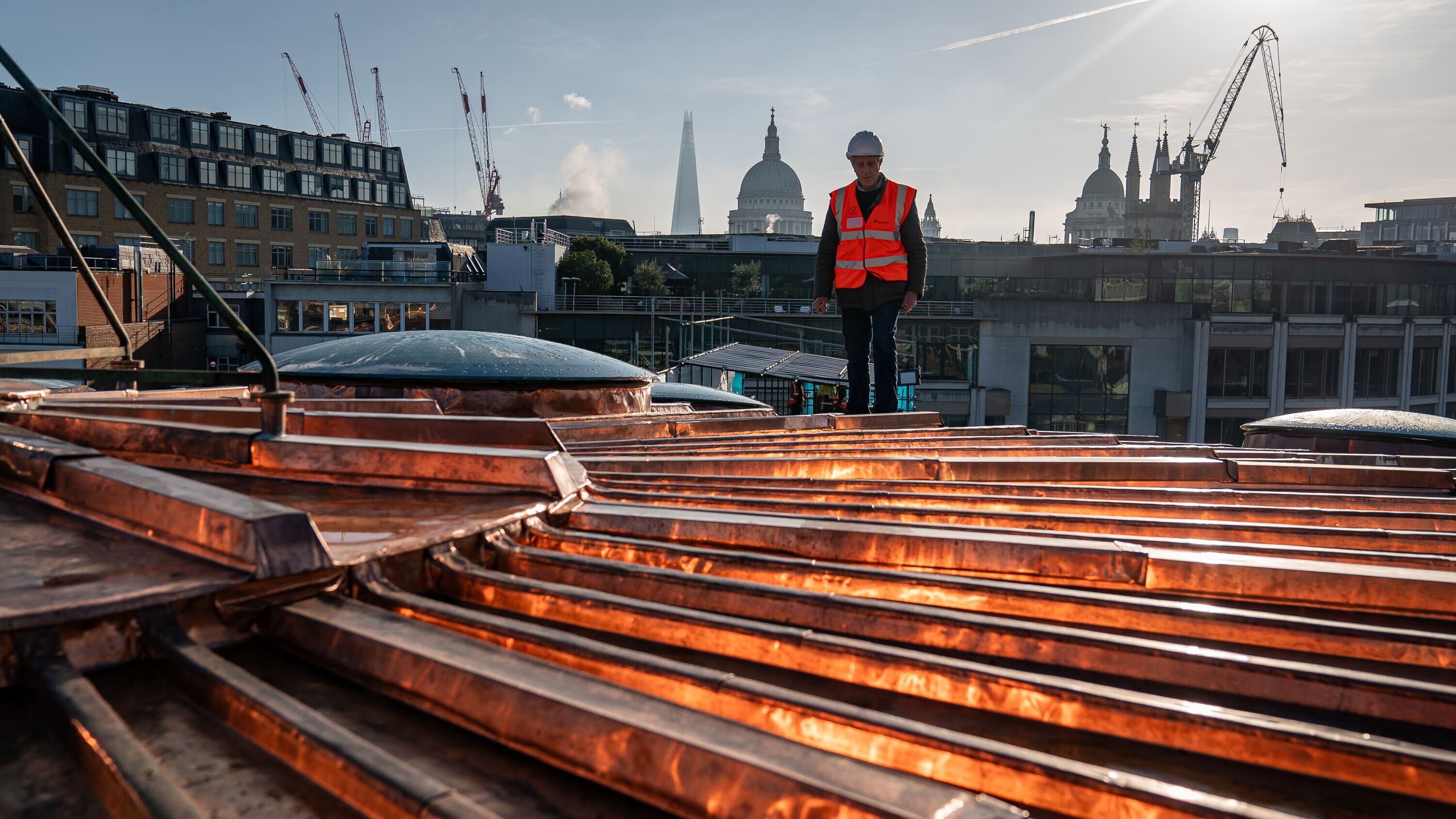 Chris Johnson, 82, who worked on the roof at Smithfield Market in London, as an apprentice in the 60s, walks across the refurbished copper clad Poultry Market roof, where the new Museum of London will be rehomed (Aaron Chown/PA)