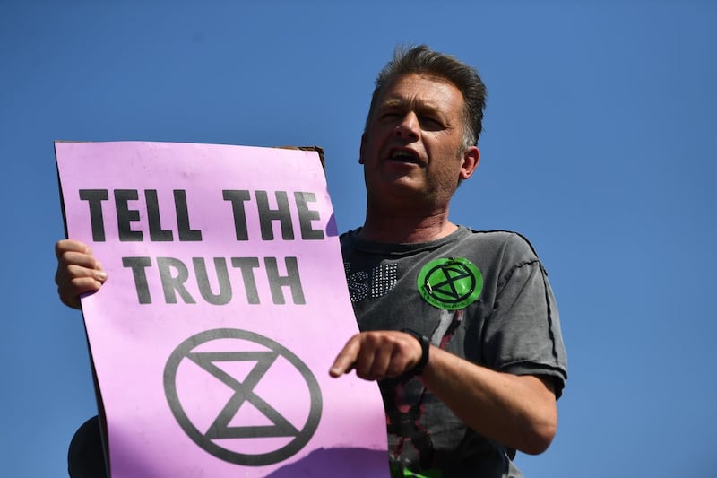 Chris Packham makes a speech on top of a bus stop during the Extinction Rebellion demonstration on Waterloo Bridge in London