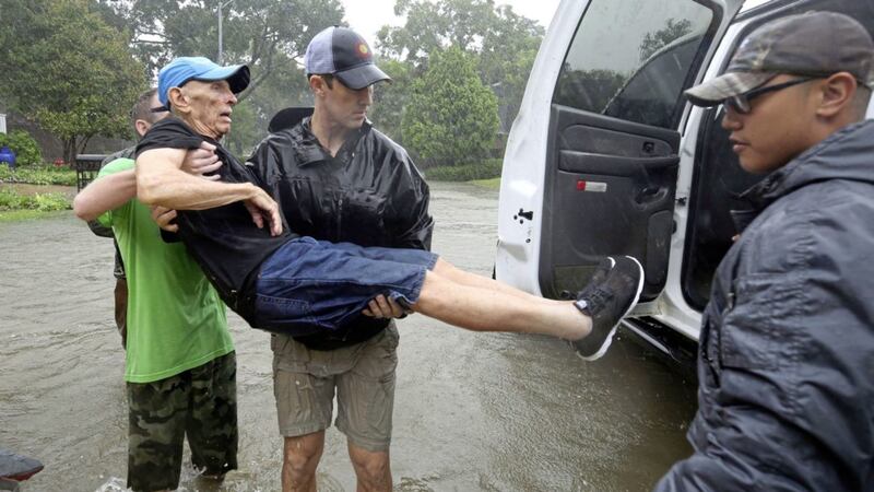 Doug Whitty is helped into a truck after being taken out of his flooded home by first responders and volunteers during Tropical Storm Harvey in Houston Picture: Godofredo A Vasquez/Houston Chronicle via AP 