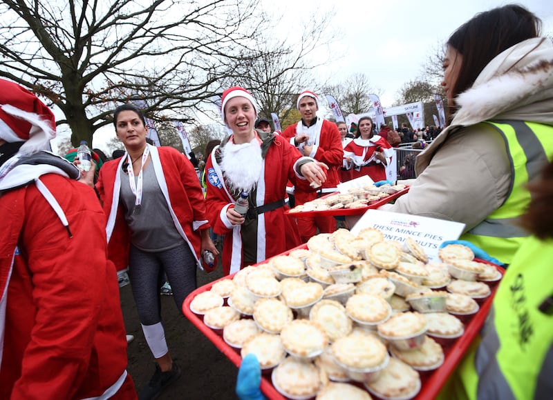 Participants take some mince pies after taking part in the London Santa Run, in Victoria Park, London