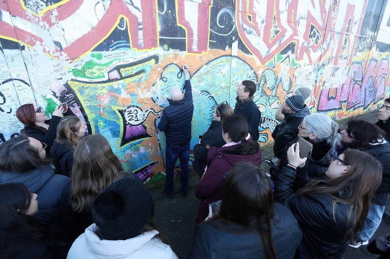 Tourists signing the peace wall at Cupar Way, Belfast. Picture by Mal McCann