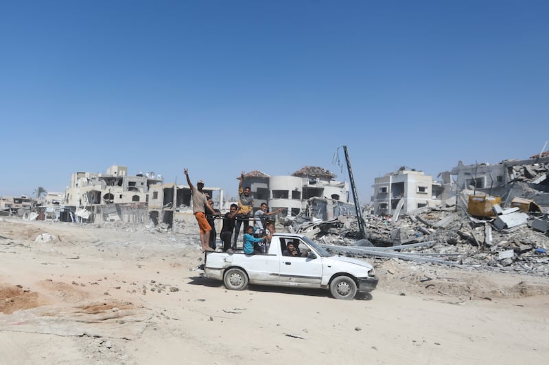 Palestinians drive by the destruction left by the Israeli air and ground offensive after they withdrew from Khan Younis, southern Gaza Strip (Ismael Abu Dayyah/AP)
