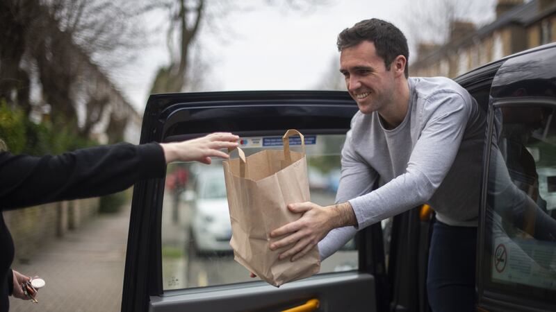 Josh Kelly loads the back of his taxi with takeaway meals to take to customers across his Islington neighbourhood.