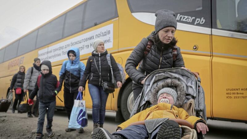 A woman pushes a pram as people from Ukraine arrive at the border crossing in Medyka, Poland, on Friday. Picture by Visar Kryeziu, Associated Press 