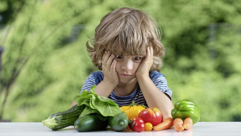 Cute little boy sitting at the table frustrated by vegetable meal, bad eating habits, nutrition and healthy eating concept. 