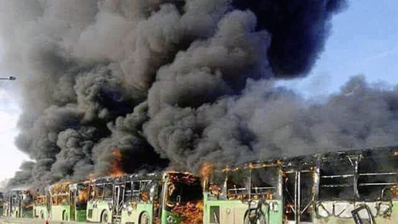 Smoke rises in green government buses, in Idlib province, Syria Picture by SANA via AP 