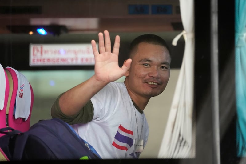 A Thai man freed after being taken hostage by Hamas waves from a bus after arriving at Suvarnabhumi International Airport