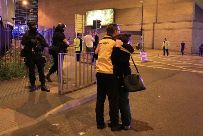 people hug as armed police stand by in manchester (Peter Byrne/PA)