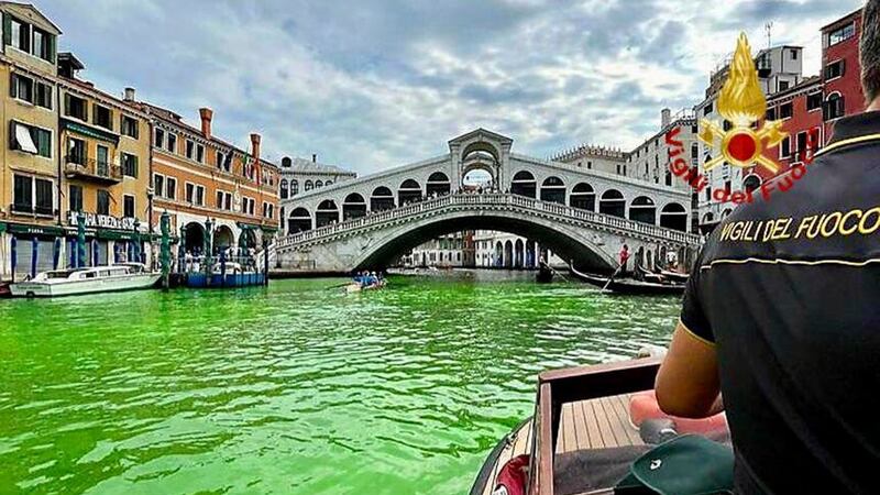 A firefighter on a boat near the arched Rialto Bridge along Venice’s historical Grand Canal as a patch of phosphorescent green liquid spreads in the water (Vigili Del Fuoco via AP/PA)