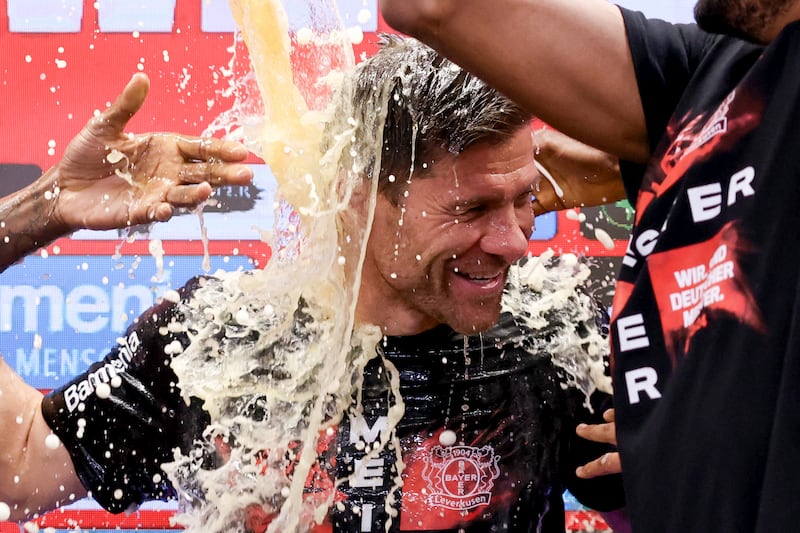 Bayer Leverkusen’s head coach Xabi Alonso is doused with beer by his players at the post-match press conference as they celebrate winning the Bundesliga (Rolf Vennenbernd/dpa via AP)