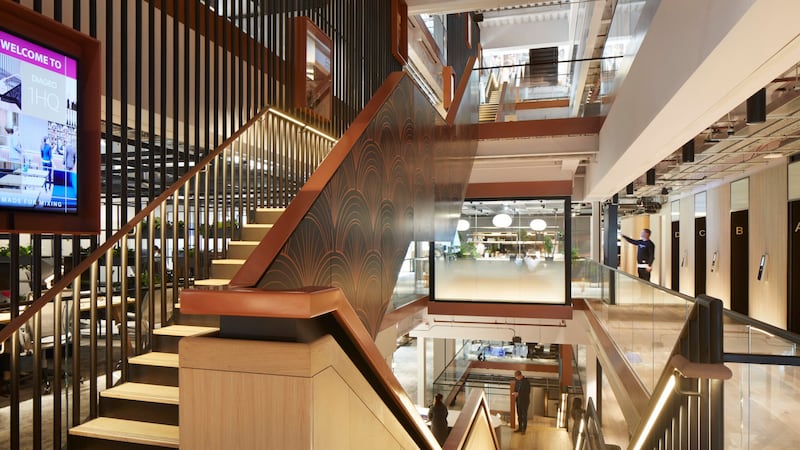 Wide angle of a modern stylish office interior showing stairs ascending to the left and another set descending to the right.