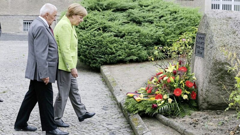 German Chancellor Angela Merkel, right, lays a wreath together with former prisoner Arno Drefke as she visits the former Stasi prison in Berlin-Hohenschoenhausen, Germany. Merkel says the government is committed to helping maintain the memorial at a former East German secret police prison, calling it an &quot;authentic and painful&quot; reminder of communist era excesses. Picture: Wolfgang Kumm/AP 