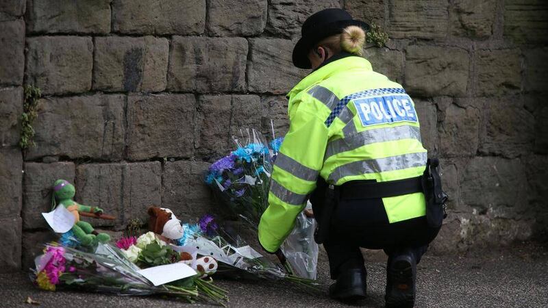 A police officer places floral tributes near a construction site where seven-year-old Conley Thompson&#39;s body was found  