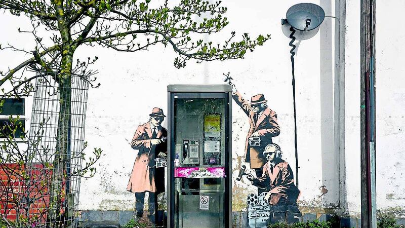 The Spy Booth mural depicts three 1950s-style agents, wearing brown trench coats and trilby hats, using devices to tap into conversations at a telephone box &nbsp;
