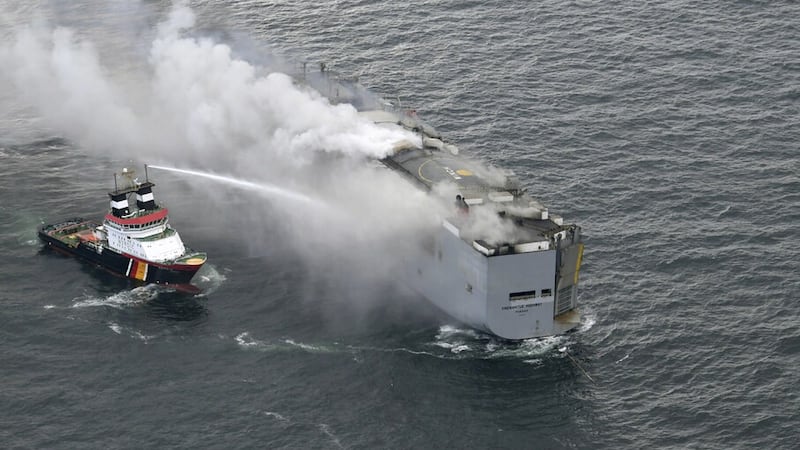 A boat sprays water on to the freight ship where a fire broke out on (Kustwacht Nederland/Coast Guard Netherlands via AP)