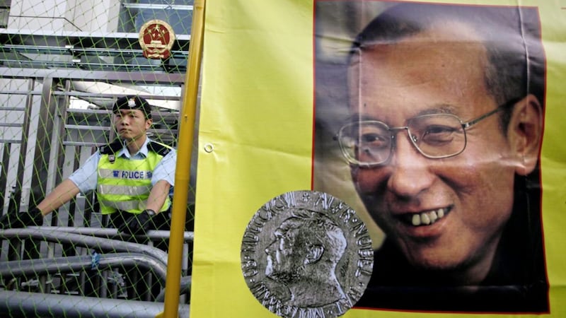 A police officer stands guard beside a picture of jailed Chinese dissident Liu Xiaobo outside the Chinese government liaison office in Hong Kong in 2010 