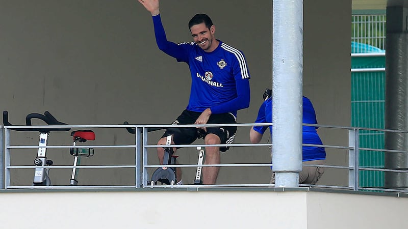 Kyle Lafferty waves whilst he sits on an exercise bike overlooking his team's training session at the Parc de Montchervet&nbsp;