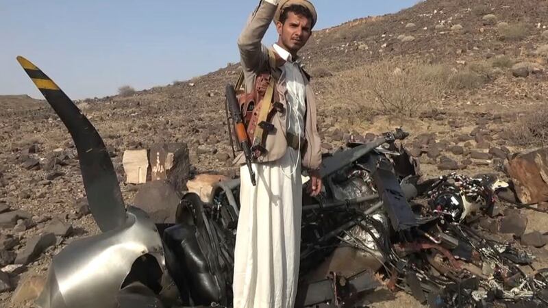 A Houthi fighter celebrates in front of what they said is debris of an American MQ9 aerial vehicle (Houthi Media Office, via AP)