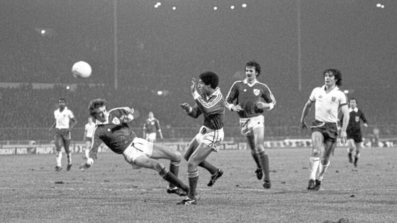 England&#39;s Kevin Keegan (r) watches as he chips over Ireland&#39;s Chris Hughton (c) and Mark Lawrenson (r) to give him his second goal of the game.. 