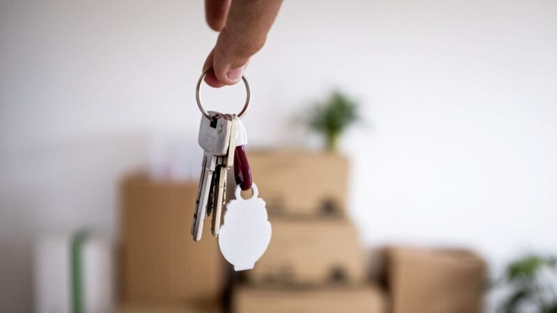 Close-up of the keys of the new empty apartment with moving boxes on the floor 