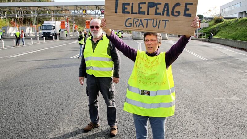 A demonstrator holds a placard reads &quot; Free Toll&quot; as they open the toll gates on motorway near Biarritz, southwestern France, Tuesday. French Prime Minister Edouard Philippe announced a suspension of fuel tax hikes Tuesday, a major U-turn in an effort to appease a protest movement that has radicalized and plunged Paris into chaos last weekend. Picture by Bob Edme/AP 