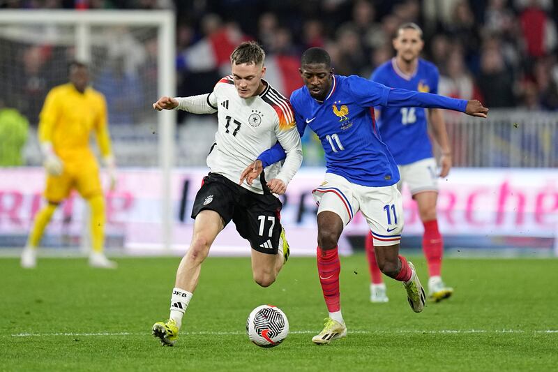 Florian Wirtz, left, challenges for the ball with France’s Ousmane Dembele (Laurent Cipriani/AP)