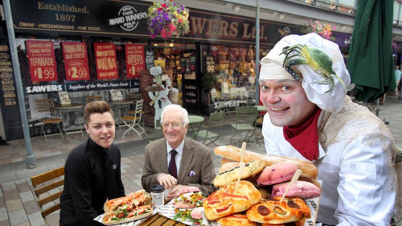 Edward Callaghan, centre, is tempted by Kieran Sloan of Sawers Deli and chef Barney to take part in Belfast Bred, a walking tour of city eateries, presented by Kabosh Theatre Company Picture by Cliff Donaldson 