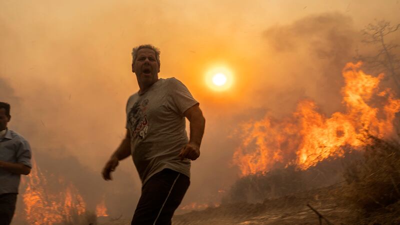 A local reacts as flames burn trees in the village of Gennadi on the Aegean Sea island of Rhodes (Petros Giannakouris/AP)
